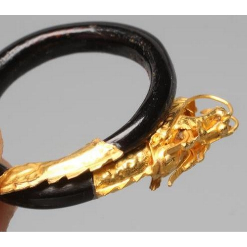 506 - A BANGLE AND MATCHING RING, probably Chinese, possibly lacquered wood, each with a yellow metal drag... 