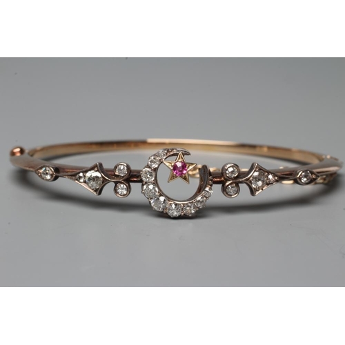 507 - A VICTORIAN STIFF HINGED BANGLE, the upper section centred by a diamond set crescent moon and ruby s... 