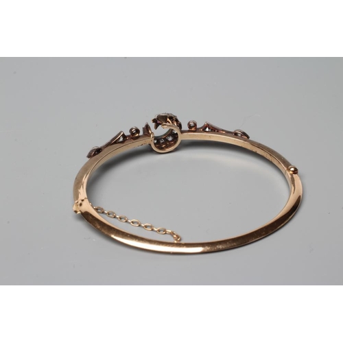 507 - A VICTORIAN STIFF HINGED BANGLE, the upper section centred by a diamond set crescent moon and ruby s... 