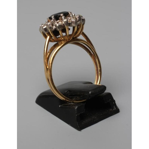 513 - A SAPPHIRE AND DIAMOND CLUSTER RING, the oval facet cut sapphire claw set to a border of numerous mi... 