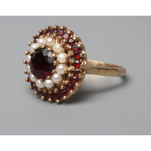 514 - A GARNET AND SEED PEARL CLUSTER RING, point and claw set to a plain shank stamped 9ct, size R (Est. ... 