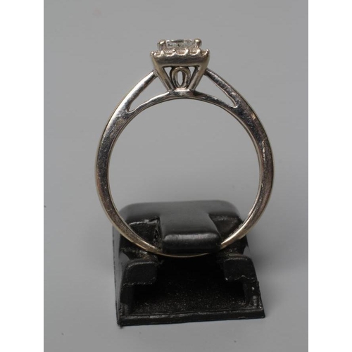 518 - A DIAMOND CLUSTER RING, the central square cut stone claw set to an open border of sixteen small rou... 