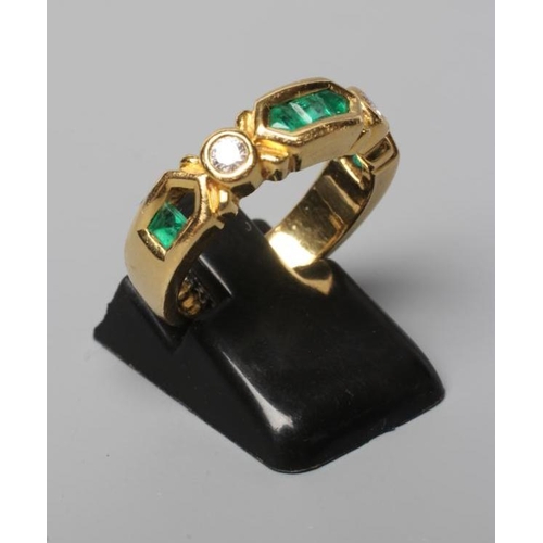 545 - AN EMERALD AND DIAMOND HALF HOOP RING, the heavy cast panel centred by three channel cut emeralds fl... 