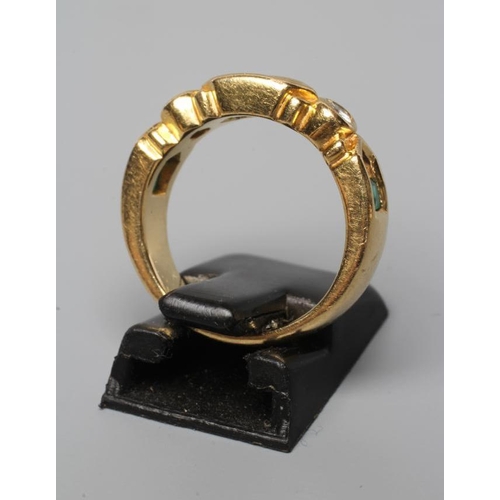 545 - AN EMERALD AND DIAMOND HALF HOOP RING, the heavy cast panel centred by three channel cut emeralds fl... 