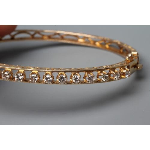 554 - A DIAMOND SET STIFF HINGED BANGLE, the upper section claw set with seventeen small round brilliant c... 