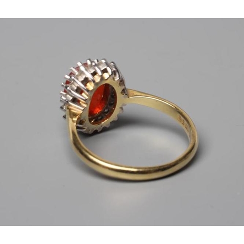 555 - A FIRE OPAL AND DIAMOND CLUSTER RING, the oval facet cut opal within a border of eighteen point set ... 