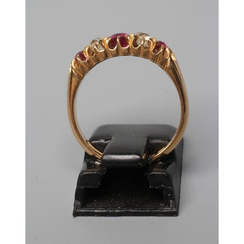 569 - A LATE VICTORIAN RUBY AND DIAMOND RING, the oval facet cut central ruby flanked by two old brilliant... 