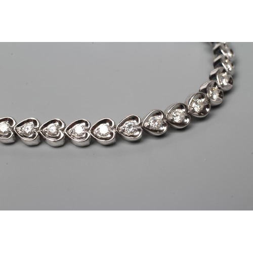 582 - A DIAMOND TENNIS BRACELET, the forty one round brilliants in rub-over heart shaped links, clasp stam... 