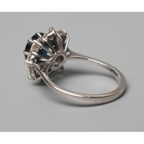 586 - A SAPPHIRE AND DIAMOND CLUSTER RING, the circular Australian sapphire facet cut and claw set to a bo... 