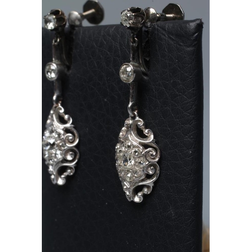 604 - A PAIR OF DIAMOND DROP EARRINGS of open scroll quatrefoil form, pave with numerous stones, the screw... 