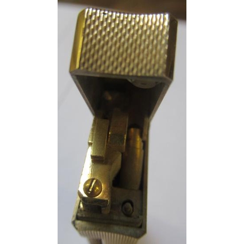 152 - A DUNHILL 9CT GOLD ROLLAGAS CIGARETTE LIGHTER of plain oblong form with engine turning, 2 1/2