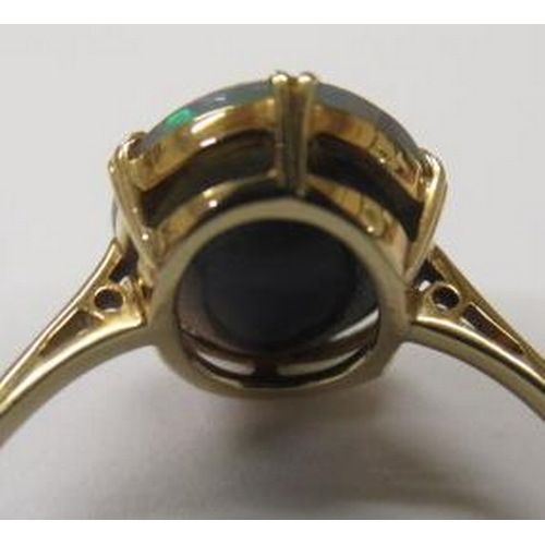 429 - T. GAUNT - a black opal ring, the oval cabochon polished stone claw set to a plain shank, stamped 15... 