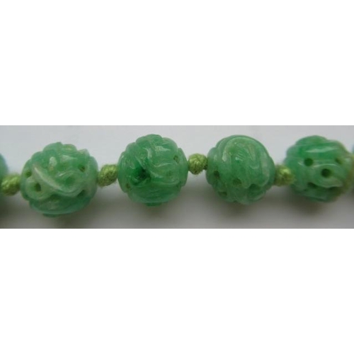 474 - A CHINESE JADE NECKLACE, the twenty nine spherical beads carved and pierced with scrolling foliage, ... 