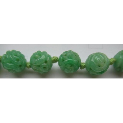 474 - A CHINESE JADE NECKLACE, the twenty nine spherical beads carved and pierced with scrolling foliage, ... 