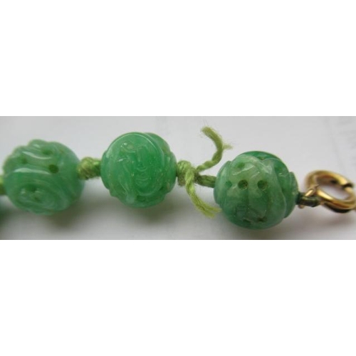 474 - A CHINESE JADE NECKLACE, the twenty nine spherical beads carved and pierced with scrolling foliage, ... 