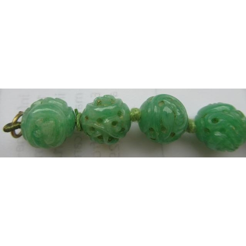 474 - A CHINESE JADE NECKLACE, the twenty nine spherical beads carved and pierced with scrolling foliage, ... 