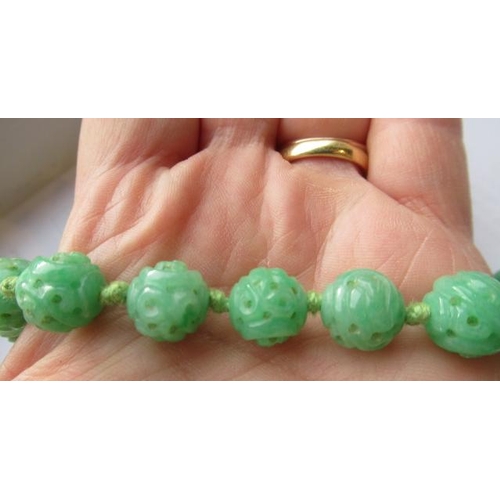 474 - A CHINESE JADE NECKLACE, the twenty nine spherical beads carved and pierced with scrolling foliage, ... 