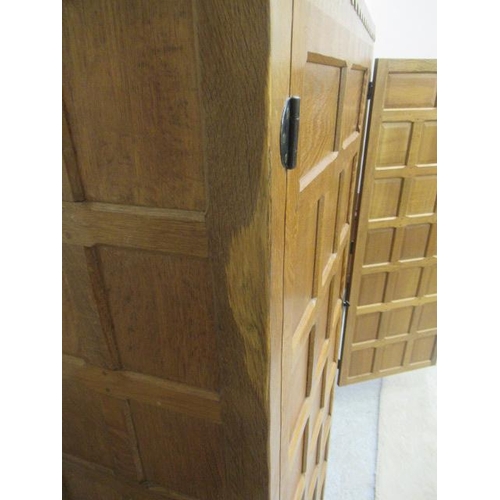 880 - A ROBERT THOMPSON ADZED OAK WARDROBE of oblong multi panelled form with half penny moulded cornice, ... 