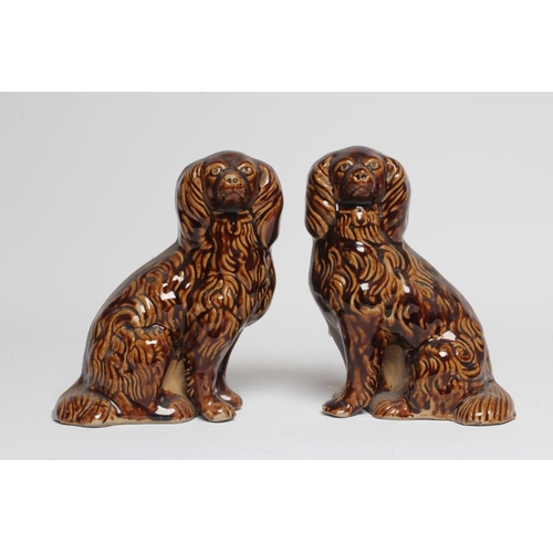 38 - A PAIR OF EARLY VICTORIAN TREACLE GLAZED HEAVY STONEWARE SPANIELS modelled with a free standing fore... 