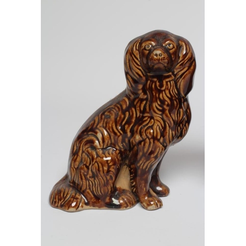 38 - A PAIR OF EARLY VICTORIAN TREACLE GLAZED HEAVY STONEWARE SPANIELS modelled with a free standing fore... 