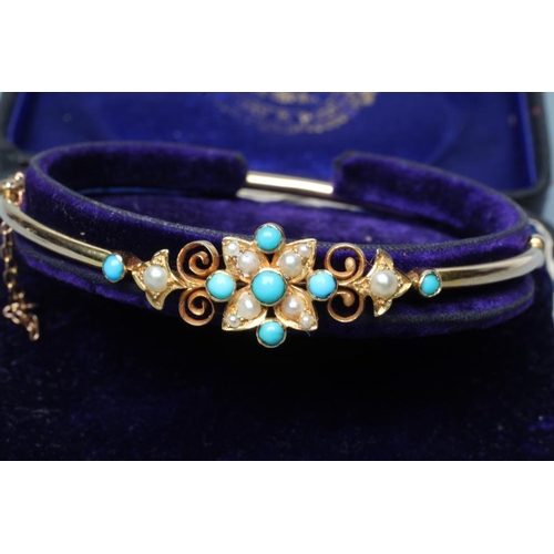 382 - AN EDWARDIAN STIFF HINGED BANGLE, the upper section centred by a turquoise bead and seed pearl flowe... 