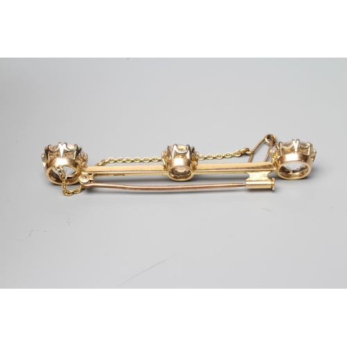 388 - A BAR BROOCH, the knife edge bar claw set with three large facet cut stones, possibly white sapphire... 