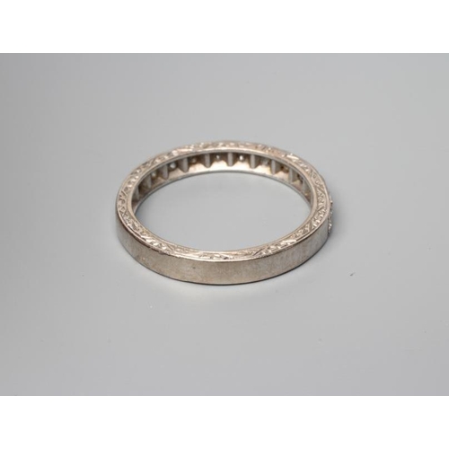 389 - AN ELEVEN STONE DIAMOND HALF HOOP RING, the old cut stones point set to a white shank with scroll en... 