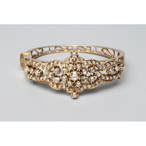 411 - A DIAMOND STIFF HINGED BANGLE, the open upper section set with numerous mix cut stones in rub-over s... 