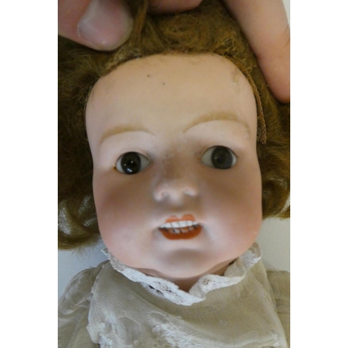 101 - A German bisque socket head character doll, with brown glass fixed eyes, moulded grinning teeth, ben... 