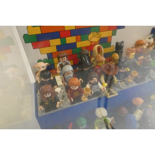 229 - A perspex display case of Lego figures, comprising 68 characters, 3 cats, an owl and a penguin, inlc... 