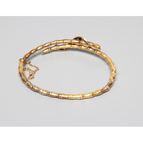 177 - A LATE VICTORIAN STIFF HINGED FAUX BAMBOO BANGLE, the open and over lapping upper section tied by an... 