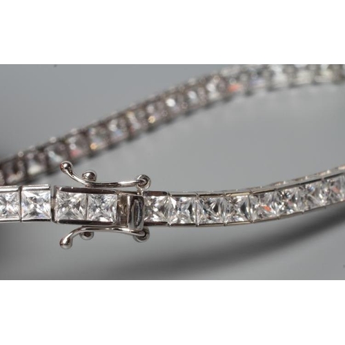 180 - A TENNIS BRACELET, the sixty one cubic zirconia channel set to a plain white frame, stamped 375 (Est... 