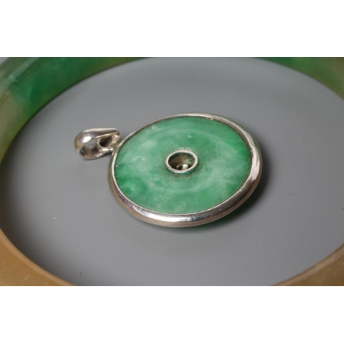 187 - A POLISHED JADE BANGLE of D form, 37g, together with a silver mounted jade Shou pendant, stamped 925... 