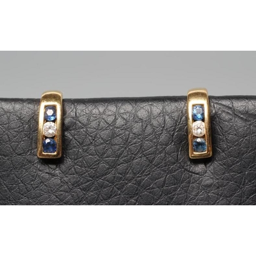 193 - A SMALL PAIR OF SAPPHIRE AND DIAMOND HALF HOOP EAR STUDS, channel set with a diamond flanked by two ... 