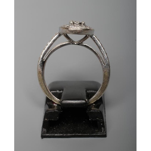 158 - DIAMOND TARGET RING, the ten stone central cluster claw set to an open border pave set with numerous... 