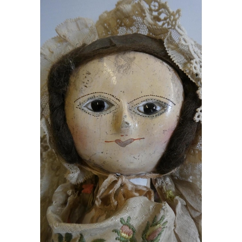 12 - An English wooden doll, c.1800, with carved and painted head and torso, brown wig, brown glass inset... 