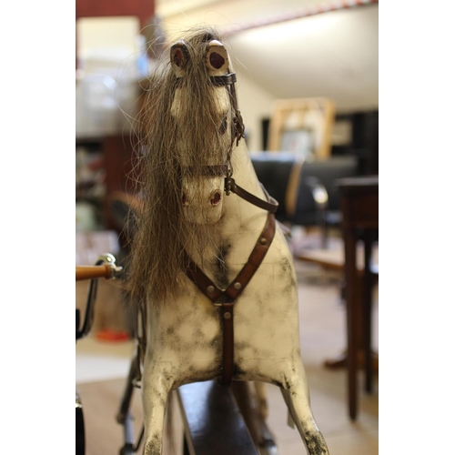 173 - A dappled grey rocking horse, with painted and carved wood body, sideways turning head, amber eyes, ... 