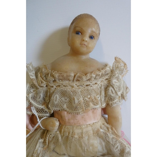 29 - A poured wax shoulder head doll, c.1840, with blue glass fixed eyes, impressed real hair, wax arms a... 