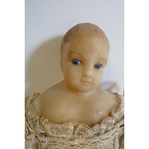 29 - A poured wax shoulder head doll, c.1840, with blue glass fixed eyes, impressed real hair, wax arms a... 