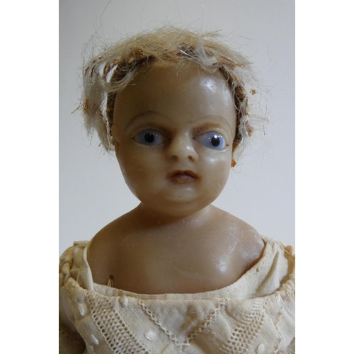 30 - A Victorian wax shoulder head doll with blue glass fixed eyes, moulded open mouth, blond wig, fabric... 