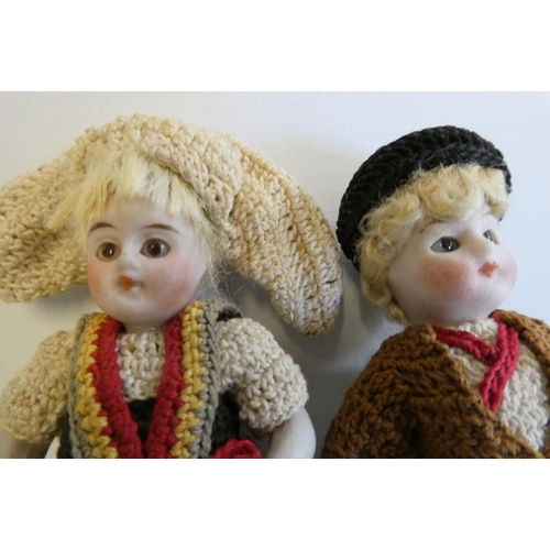 74 - A pair of all bisque doll's house dolls, with five piece bodies, brown glass fixed eyes, moulded and... 