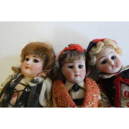 75 - Three all bisque doll's house dolls, with five piece bodies, brown glass fixed eyes, moulded and pai... 