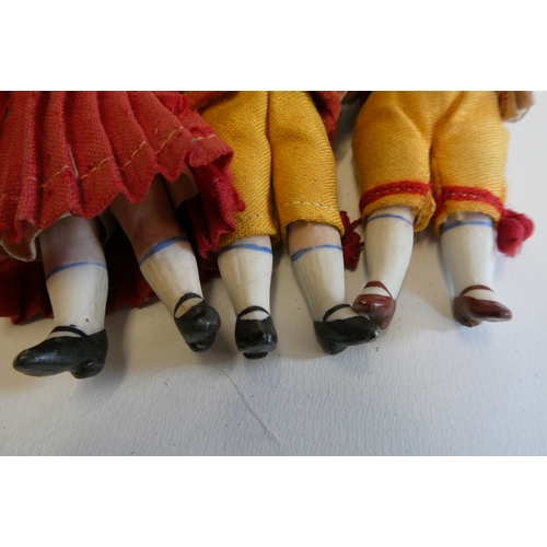 75 - Three all bisque doll's house dolls, with five piece bodies, brown glass fixed eyes, moulded and pai... 