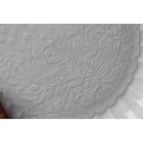 11 - A CHINESE WHITE GLAZED PORCELAIN DISH of fluted circular form centrally carved with a crane in fligh... 