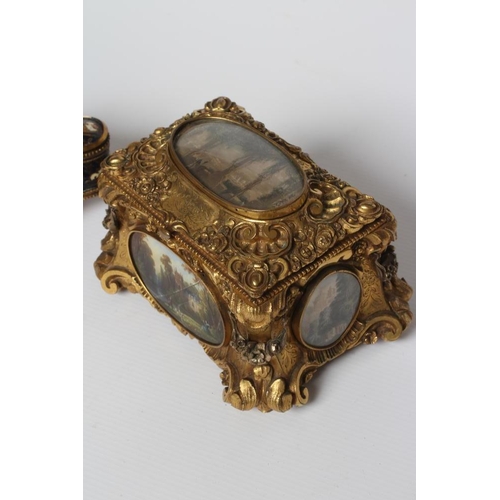 446 - A GILT METAL ROCOCO REVIVAL JEWELLERY CASKET, late 19th century, with inset landscape scenes and red... 