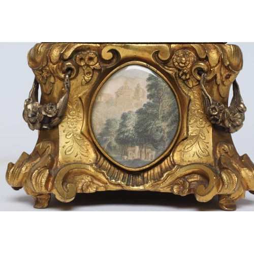 446 - A GILT METAL ROCOCO REVIVAL JEWELLERY CASKET, late 19th century, with inset landscape scenes and red... 