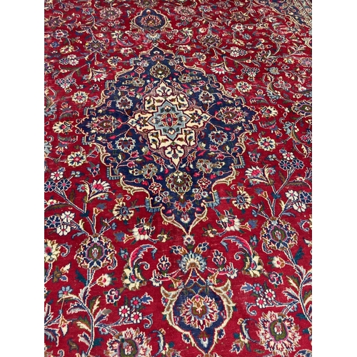 638 - A KASHAN RUG, with central floral medallion on a red ground surrounded by light and dark blue floral... 