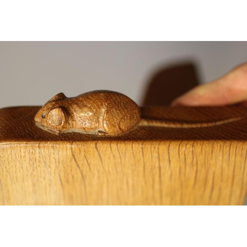 654 - A ROBERT THOMPSON ADZED OAK WALL SHELF of rounded oblong form on ogee end brackets, carved mouse tra... 