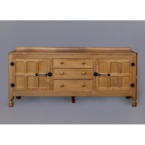 655 - A ROBERT THOMPSON ADZED OAK SIDEBOARD of canted oblong form with ledge back, moulded edged top, thre... 