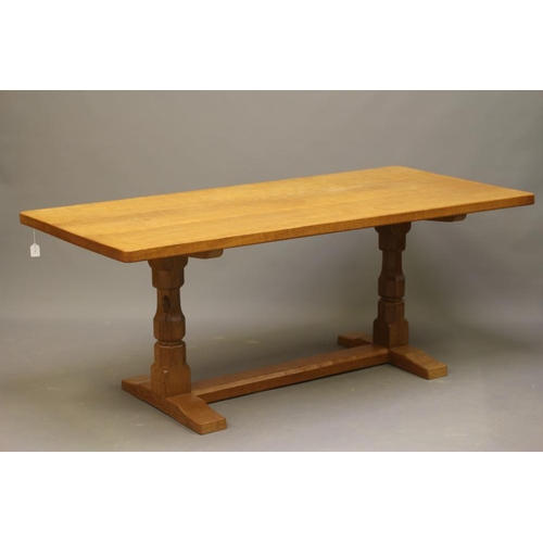 656 - A ROBERT THOMPSON ADZED OAK DINING TABLE, the rounded oblong top on trestle base with turned faceted... 